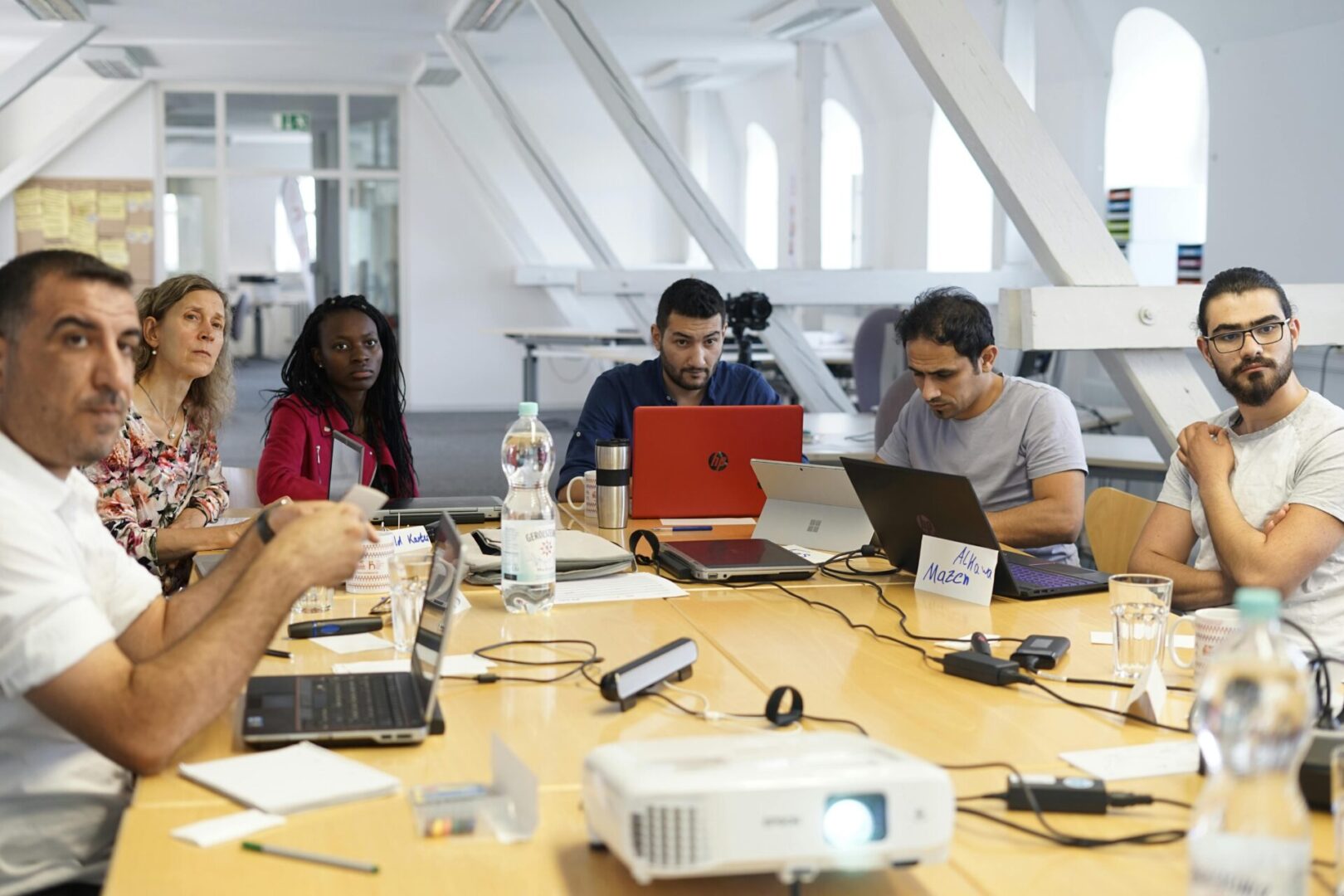 A group of people sitting around a table with laptops.