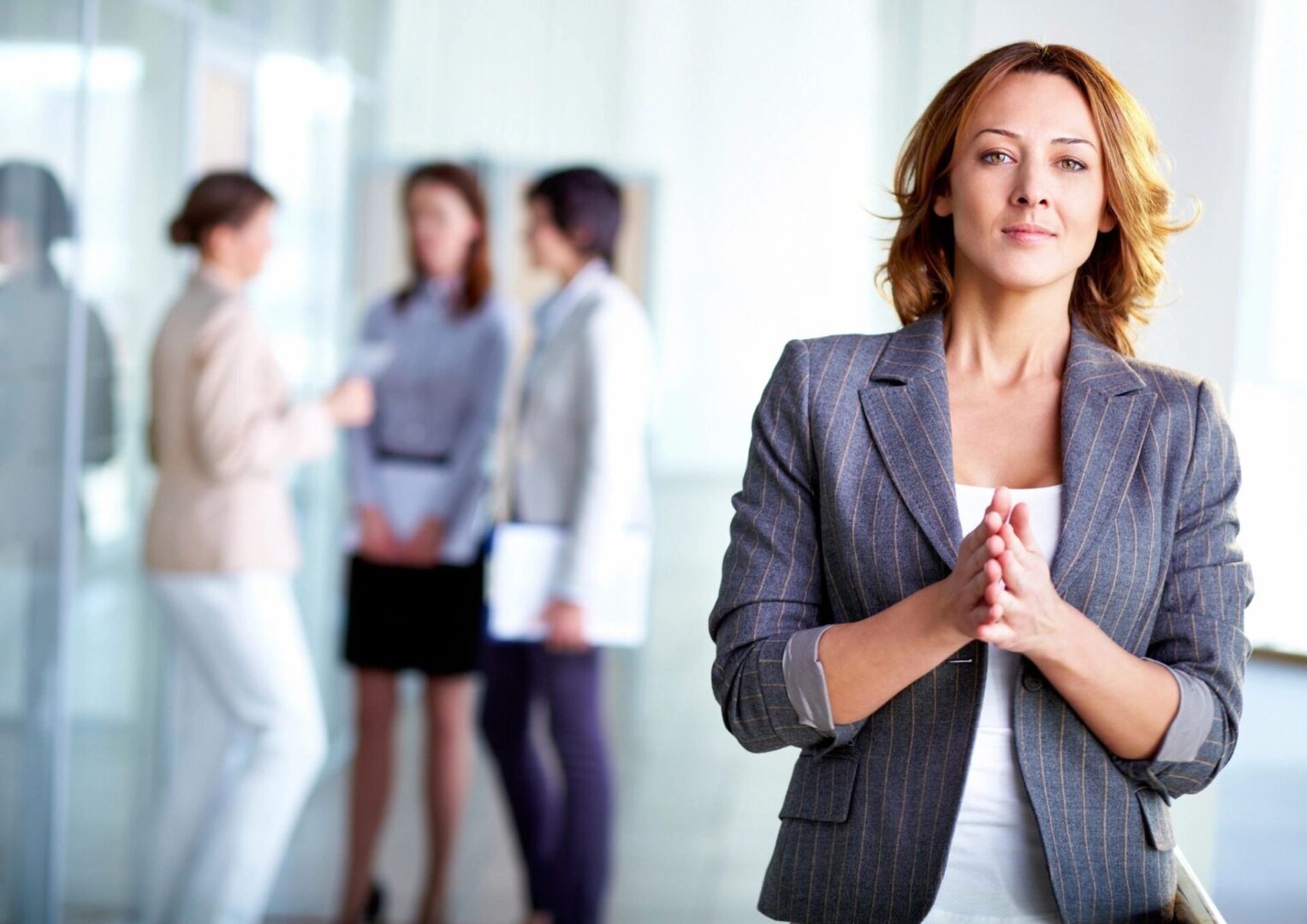 A woman in grey jacket standing next to other women.